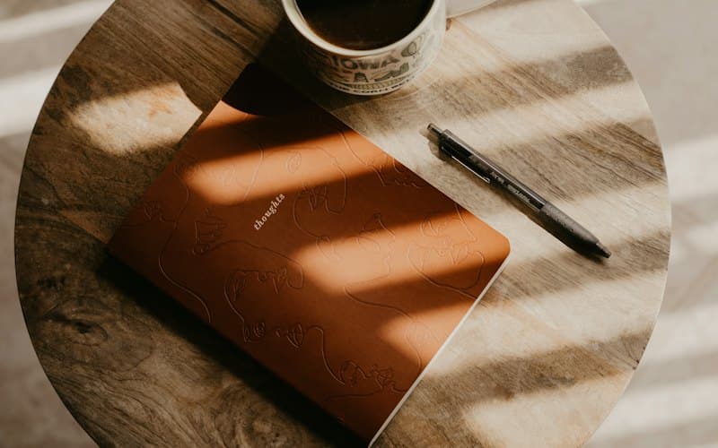 Attached image: a cup of coffee and an open notebook on a sunlit table